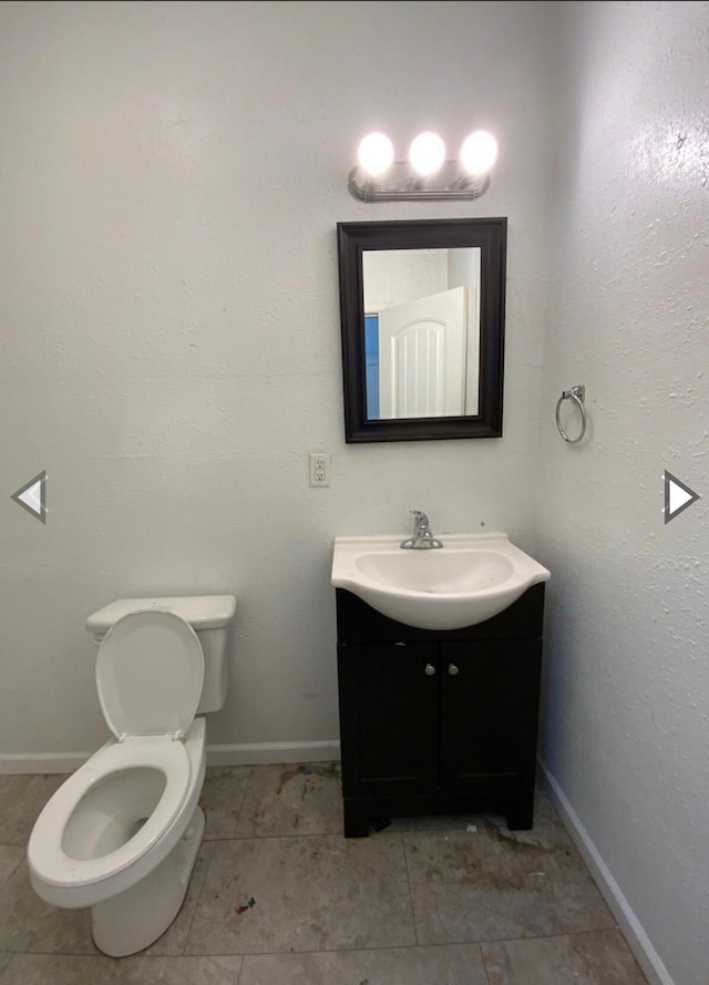 half bathroom featuring vanity, baseboards, and toilet