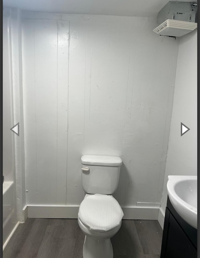 bathroom featuring wood finished floors, vanity, baseboards, toilet, and a tub to relax in