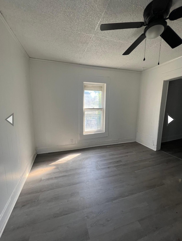empty room featuring a ceiling fan, a textured ceiling, baseboards, and dark wood-type flooring