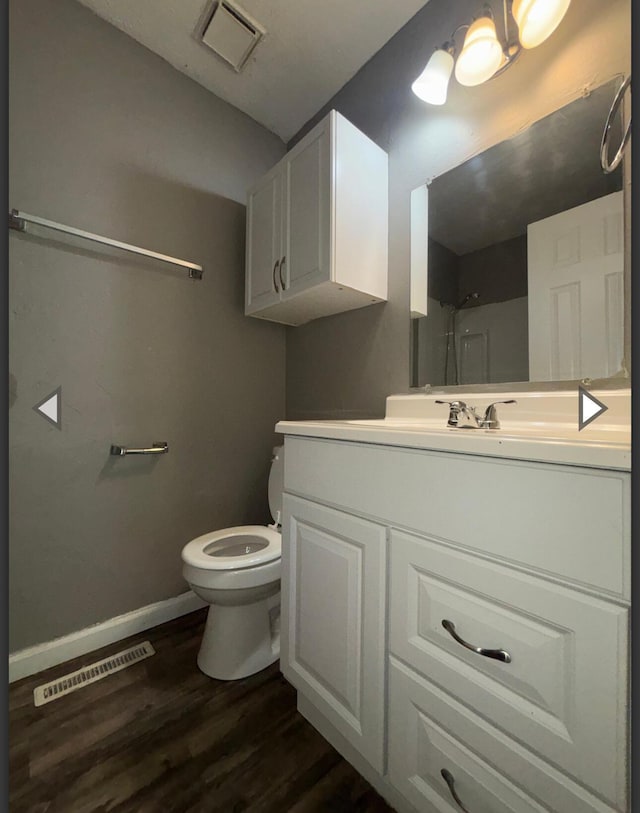 bathroom featuring vanity, toilet, wood finished floors, and visible vents
