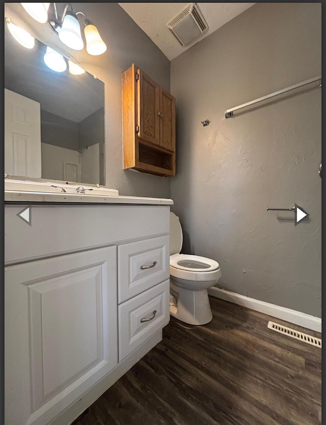 bathroom with visible vents, wood finished floors, baseboards, vanity, and toilet