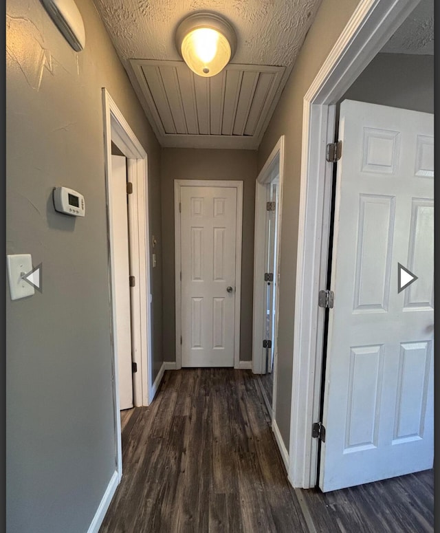 hallway featuring baseboards and dark wood-type flooring