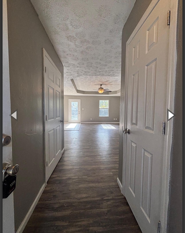 corridor with baseboards, a textured ceiling, and dark wood-style floors