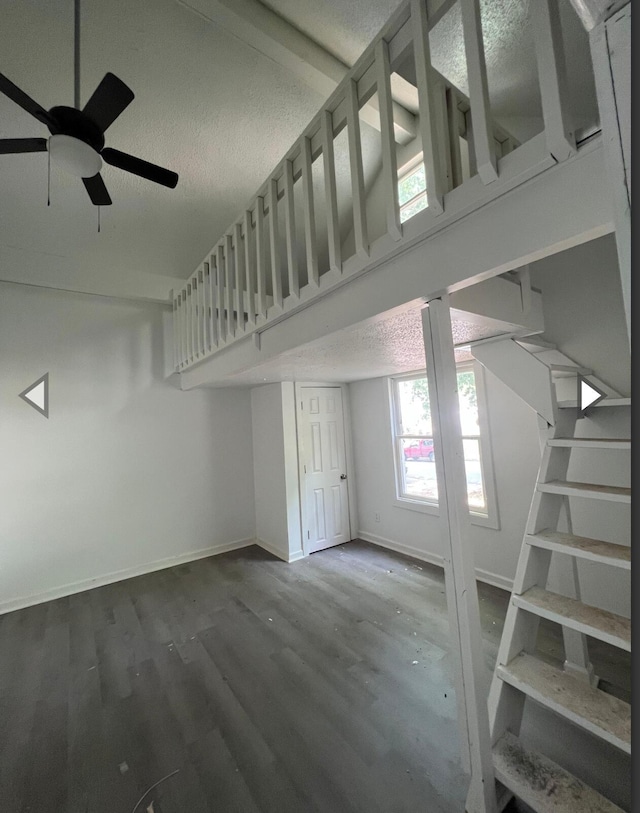unfurnished living room with stairs, wood finished floors, baseboards, a textured ceiling, and a ceiling fan