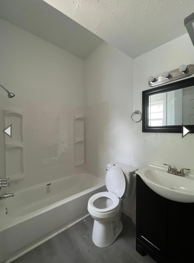 bathroom with a textured ceiling, wood finished floors, vanity, toilet, and tub / shower combination