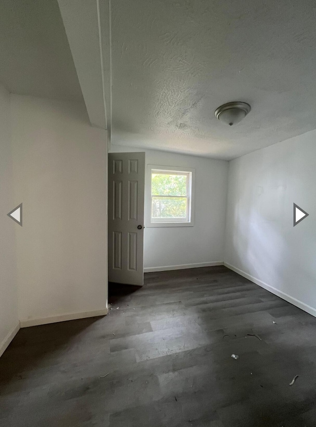 unfurnished room with baseboards, a textured ceiling, and wood finished floors