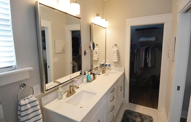 bathroom featuring a sink, a walk in closet, and double vanity