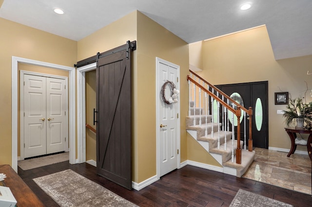 foyer entrance with a barn door, stairs, recessed lighting, baseboards, and wood finished floors