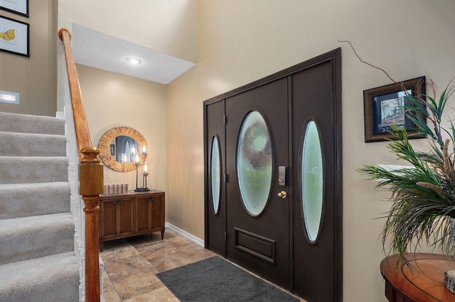 entrance foyer with baseboards, stone finish floor, and stairway