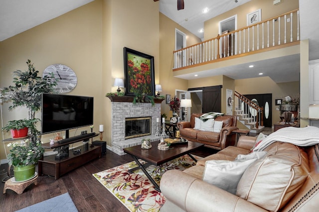 living area with a fireplace, stairs, recessed lighting, wood finished floors, and a towering ceiling