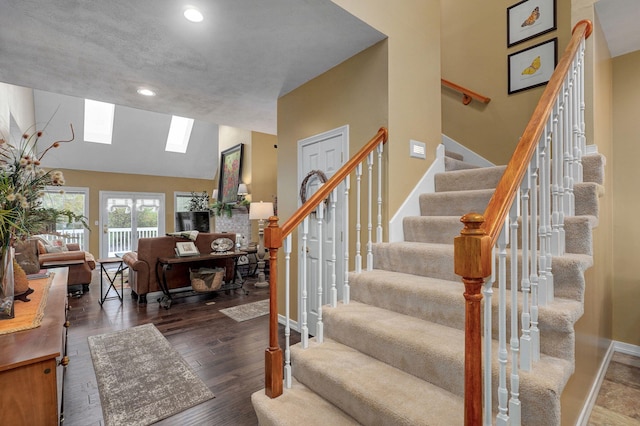 staircase with a skylight, wood finished floors, baseboards, high vaulted ceiling, and recessed lighting