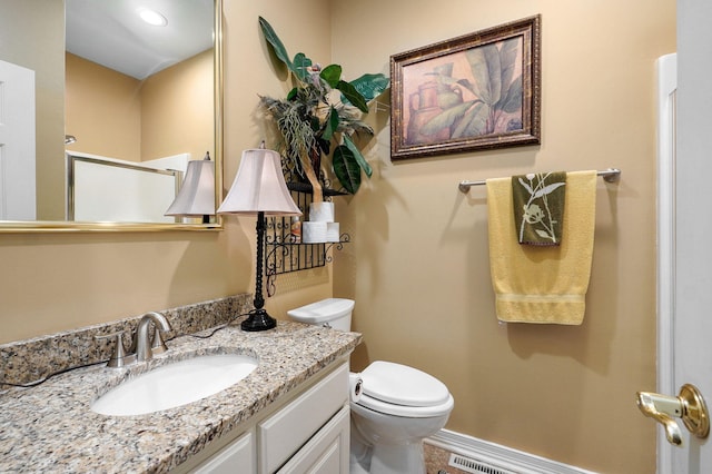 bathroom with vanity, baseboards, toilet, and a shower