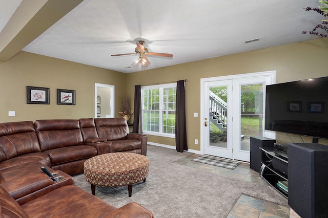 living area featuring visible vents, baseboards, and ceiling fan