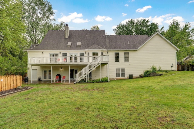 rear view of property featuring french doors, a lawn, a deck, fence, and stairs