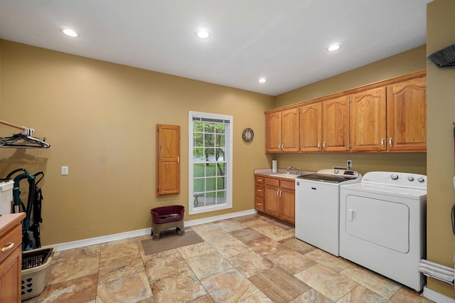 clothes washing area featuring baseboards, stone finish flooring, recessed lighting, washer and clothes dryer, and cabinet space