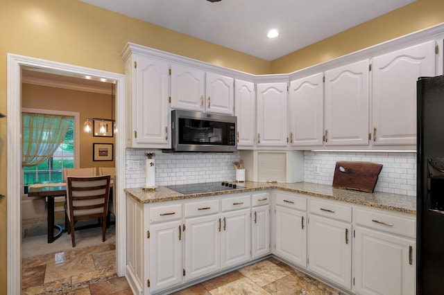 kitchen with light stone countertops, stone finish floor, white cabinets, tasteful backsplash, and black appliances