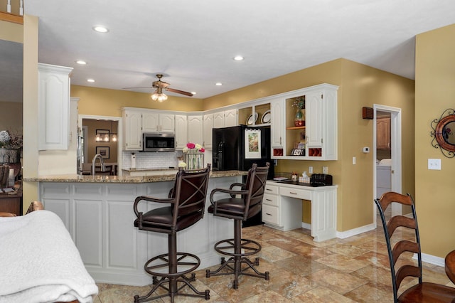 kitchen with white cabinets, a peninsula, stainless steel microwave, a ceiling fan, and baseboards