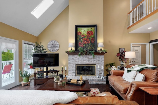 living area with a fireplace, wood finished floors, a skylight, and high vaulted ceiling