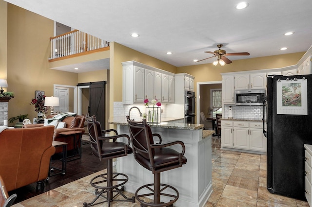 kitchen with freestanding refrigerator, stainless steel microwave, backsplash, and a peninsula