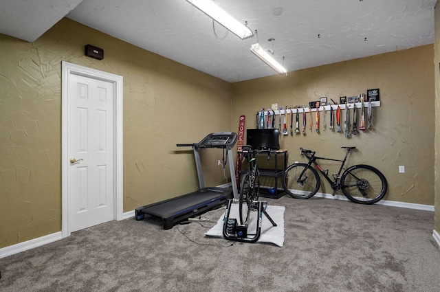 workout room with baseboards, carpet, and a textured wall
