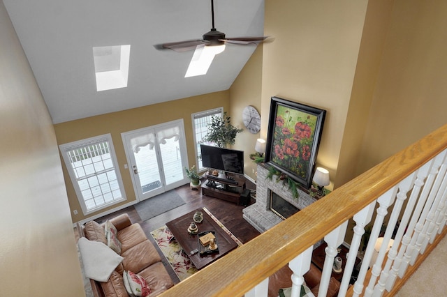 living area featuring stairs, high vaulted ceiling, a skylight, and ceiling fan