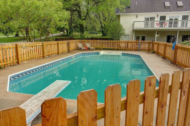 view of pool featuring a diving board, a fenced in pool, a fenced backyard, and a patio area