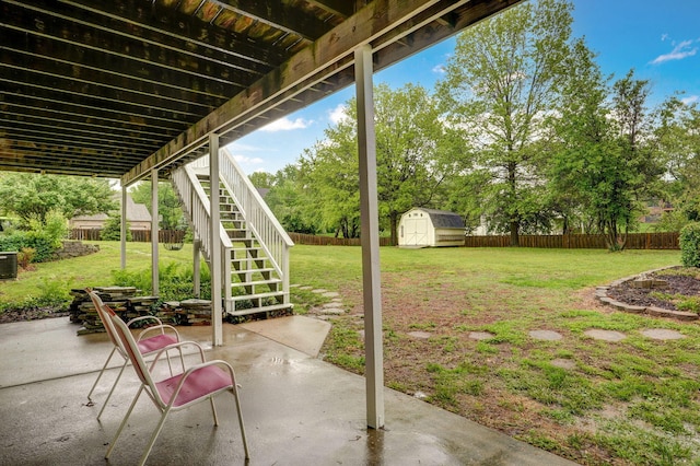 view of patio / terrace featuring stairs, a fenced backyard, a shed, and an outbuilding