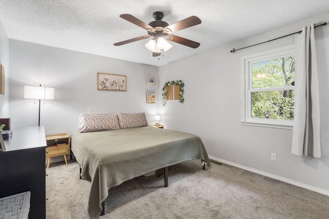 bedroom with carpet floors, a textured ceiling, baseboards, and ceiling fan