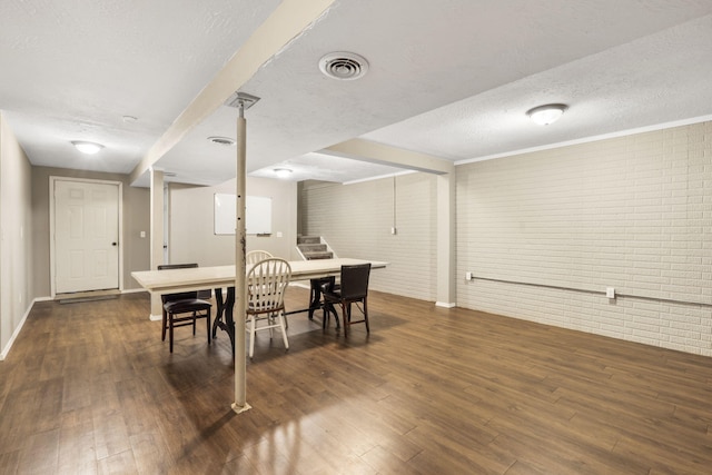 dining room featuring a textured ceiling, dark wood-style flooring, brick wall, and visible vents