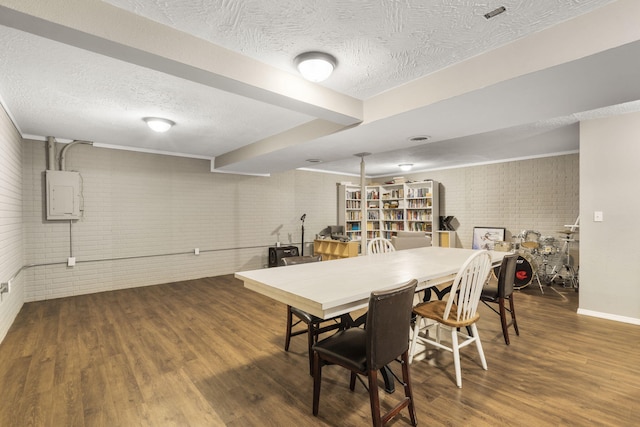 dining space featuring a textured ceiling, brick wall, baseboards, wood finished floors, and electric panel