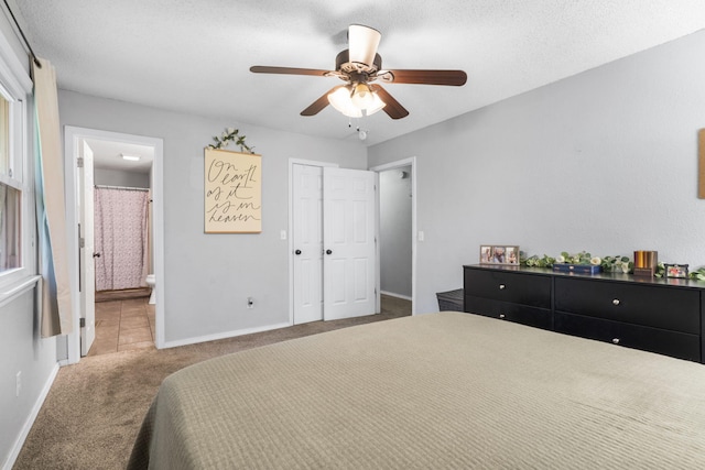 carpeted bedroom with baseboards, a ceiling fan, a textured ceiling, and ensuite bath