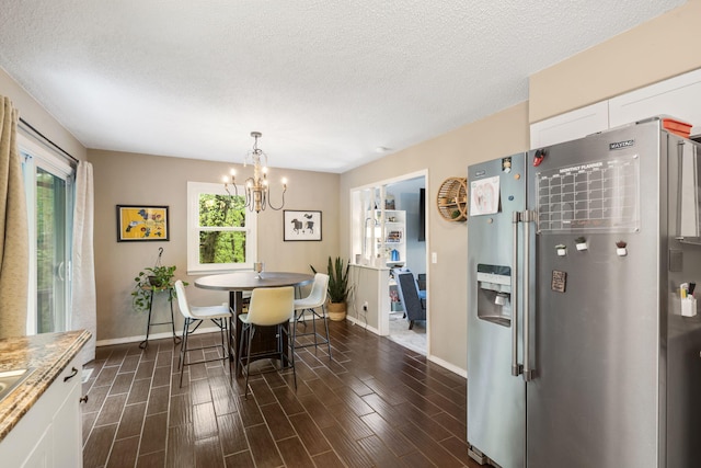dining area featuring a textured ceiling, baseboards, and a chandelier