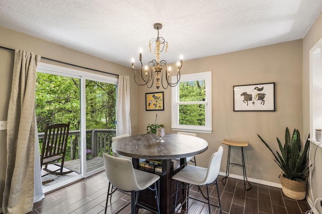 dining area featuring baseboards, wood tiled floor, a textured ceiling, and a notable chandelier