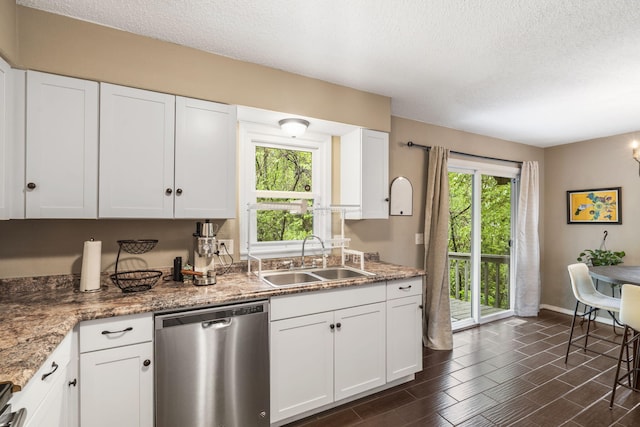 kitchen with a sink, white cabinets, stainless steel dishwasher, and a textured ceiling