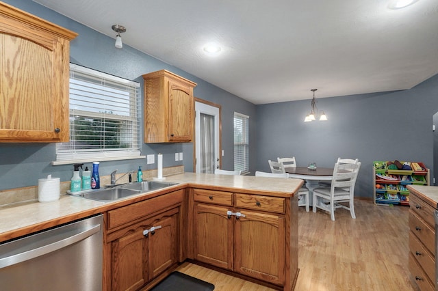 kitchen with dishwasher, a sink, light countertops, a peninsula, and light wood-style flooring