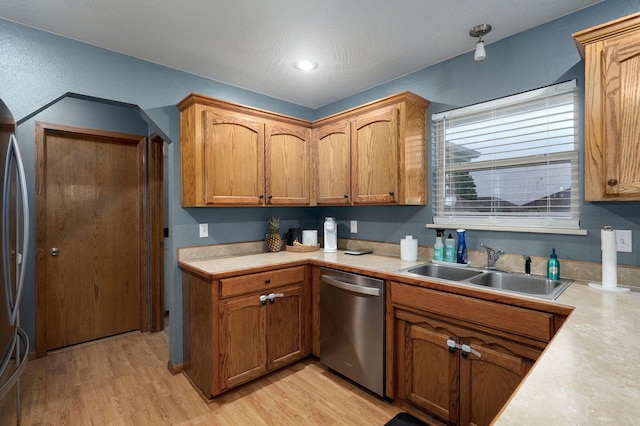 kitchen with light countertops, stainless steel appliances, brown cabinetry, and a sink