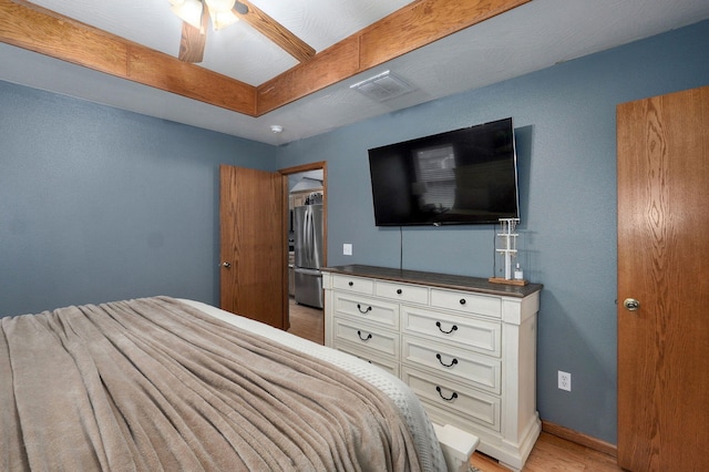 bedroom featuring ceiling fan, light wood-style floors, freestanding refrigerator, baseboards, and visible vents