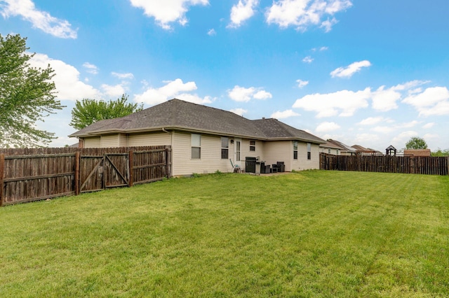 rear view of house with a lawn and a fenced backyard