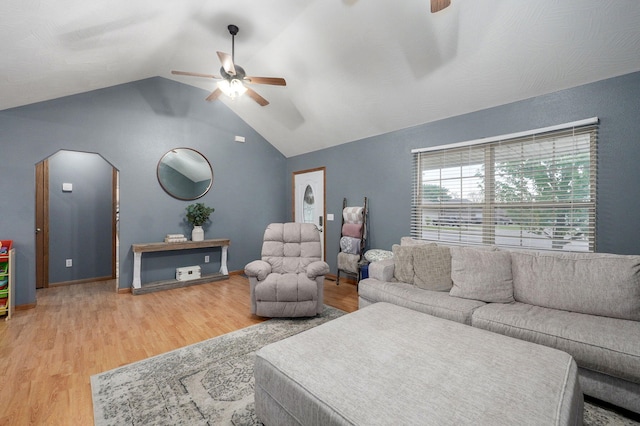 living area with arched walkways, ceiling fan, wood finished floors, and lofted ceiling