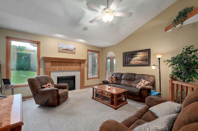 living room featuring a ceiling fan, light carpet, a tiled fireplace, arched walkways, and vaulted ceiling