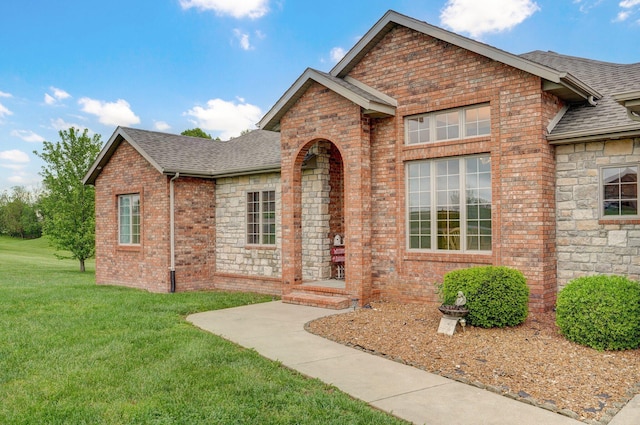 traditional home featuring brick siding, a shingled roof, and a front yard