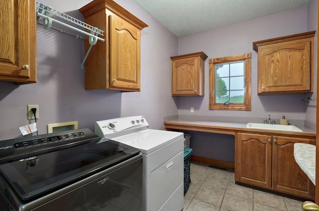 clothes washing area featuring cabinet space, light tile patterned flooring, a sink, separate washer and dryer, and a textured ceiling