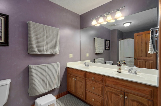 full bathroom featuring double vanity, toilet, and a sink