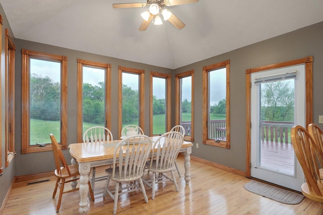 dining area with visible vents, light wood-style floors, a ceiling fan, baseboards, and vaulted ceiling