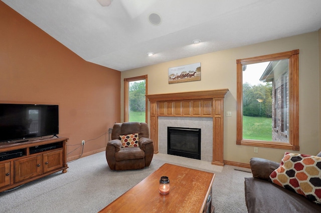 living area with a tiled fireplace, baseboards, light carpet, and lofted ceiling