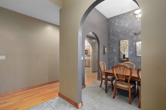 dining room featuring arched walkways, baseboards, and wood finished floors