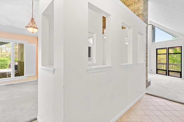 hall featuring baseboards, carpet flooring, a high ceiling, and tile patterned floors