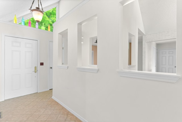 corridor with baseboards, a textured ceiling, and vaulted ceiling