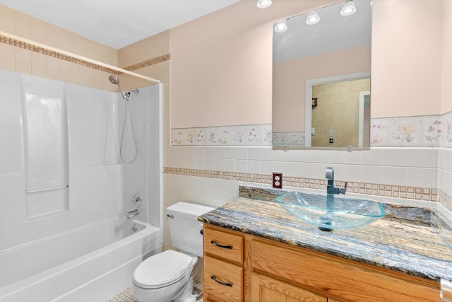 full bath with tile walls, wainscoting, vanity, toilet, and shower / bathtub combination