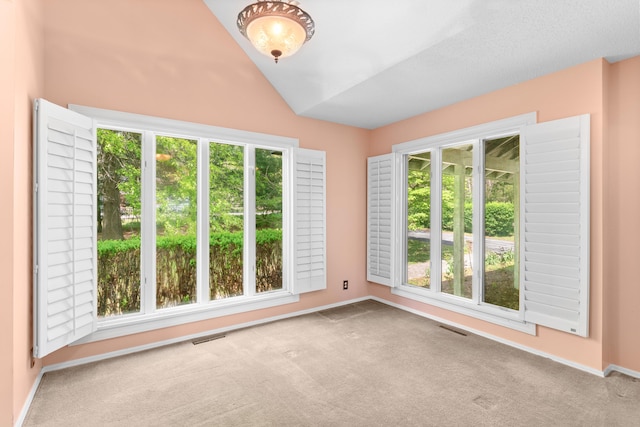unfurnished room featuring carpet floors, plenty of natural light, and lofted ceiling